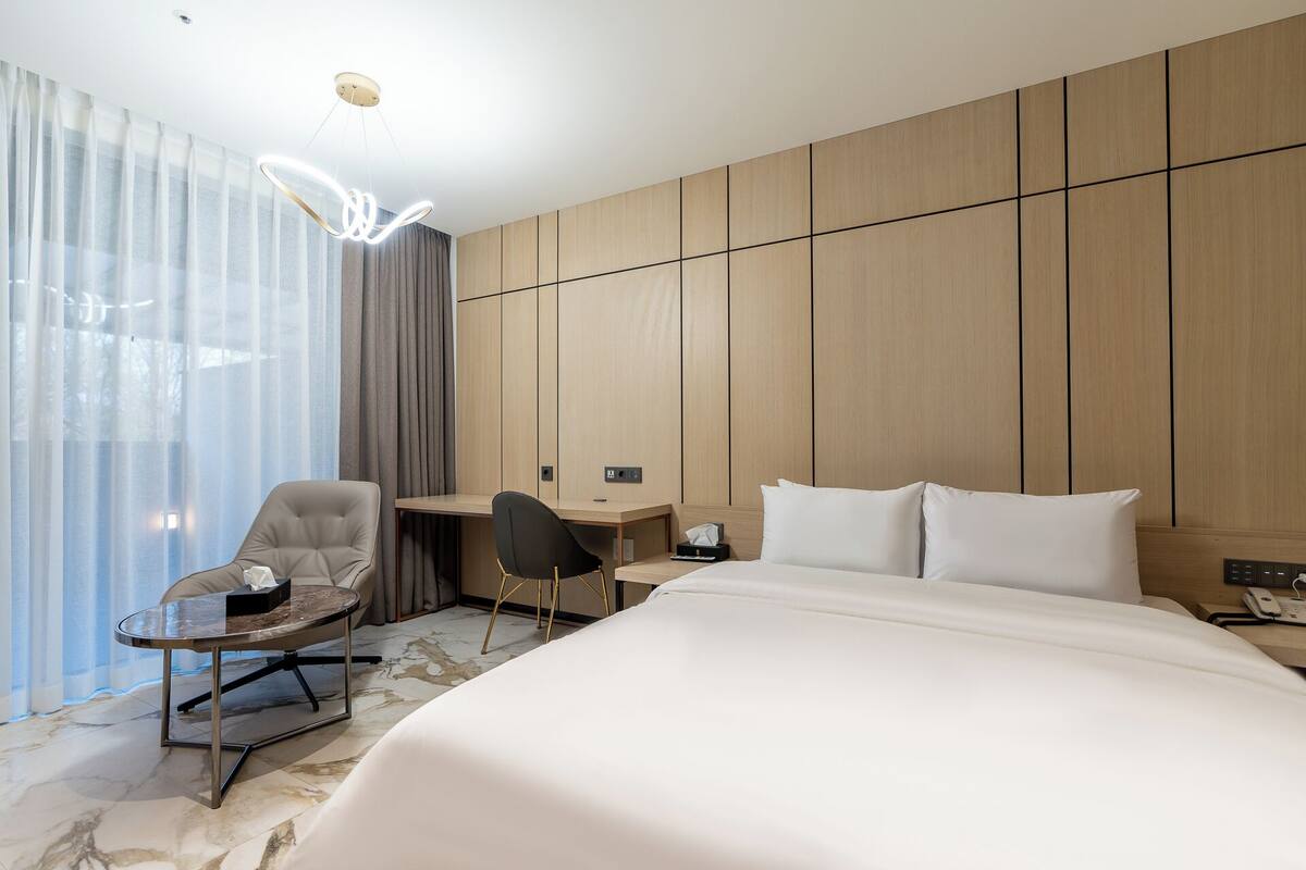 Una habitación de hotel moderna con una cama, un escritorio, una silla y una mesita.
