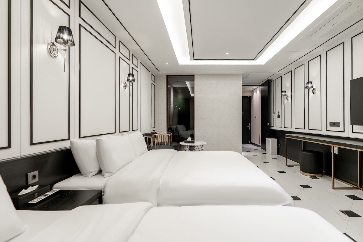 A modern hotel room with a large bed, bedside tables, a desk, and a television.