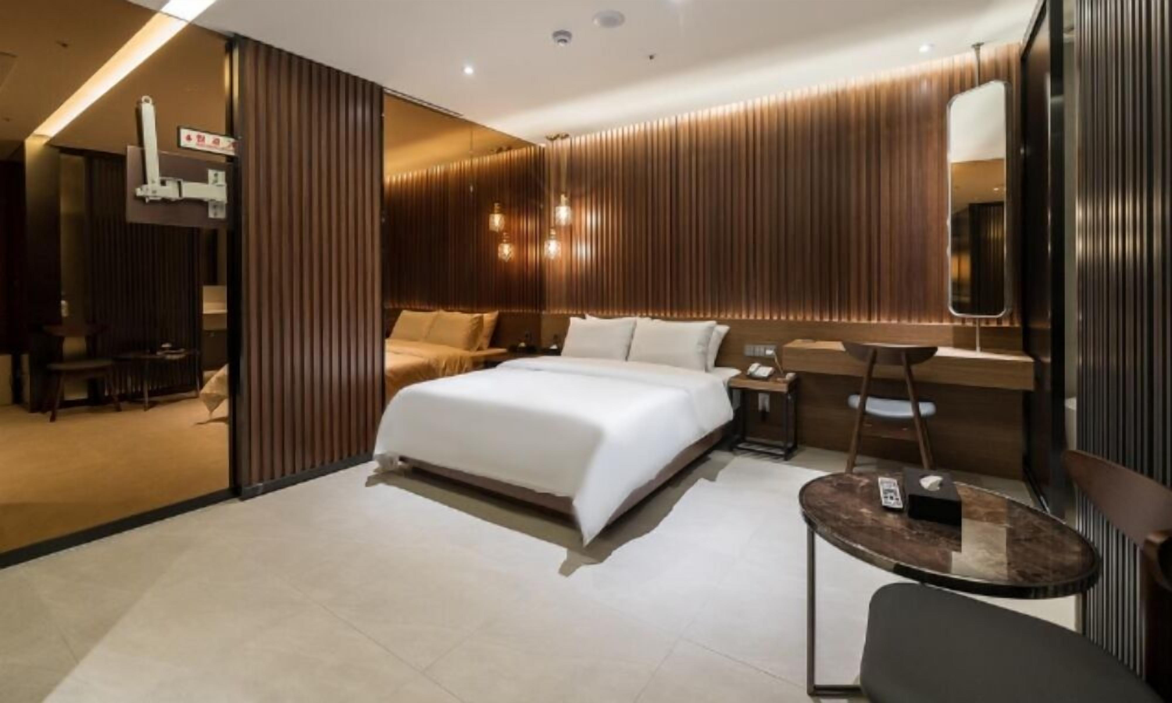 Una habitación de hotel moderna con una cama grande, un escritorio, una silla y una mesita.