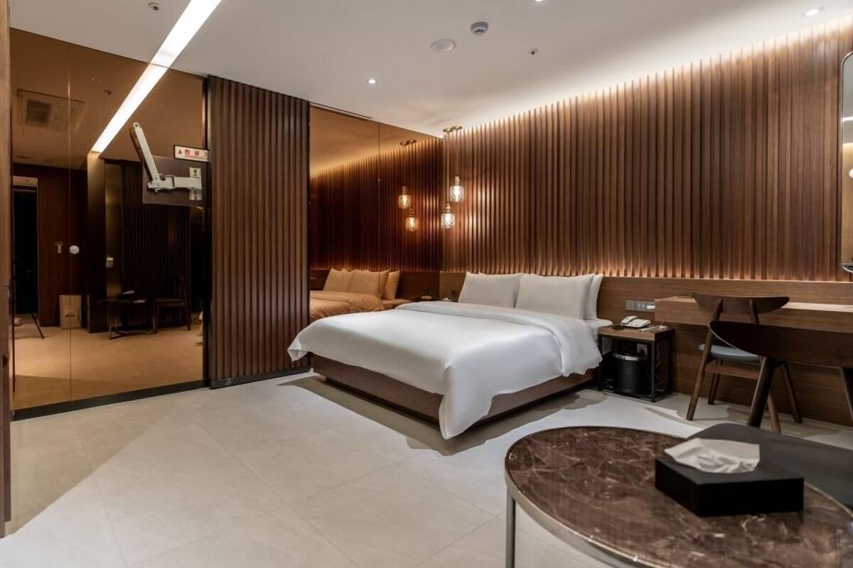 Una habitación de hotel moderna con una cama grande, un escritorio y una zona de estar.