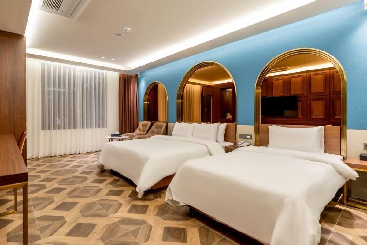 Habitación de hotel con dos camas, un escritorio y un televisor.