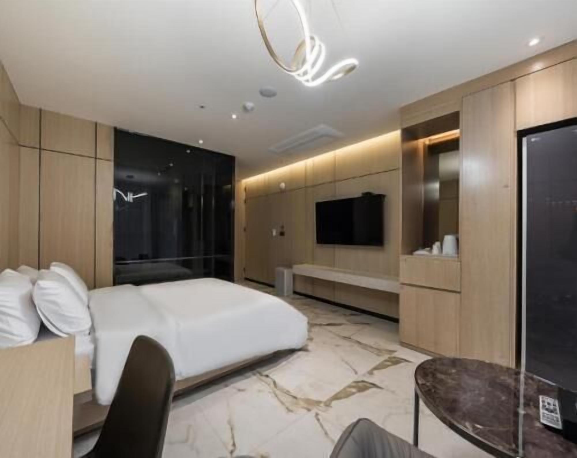 Une chambre d’hôtel moderne équipée d  ’un grand lit, d’un bureau, d’une chaise, d’un téléviseur fixé au mur et d’un mini-bar.