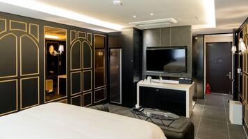 Una habitación de hotel moderna con una cama grande, un televisor montado en la pared, un tocador con espejo y un armario con espejo.
