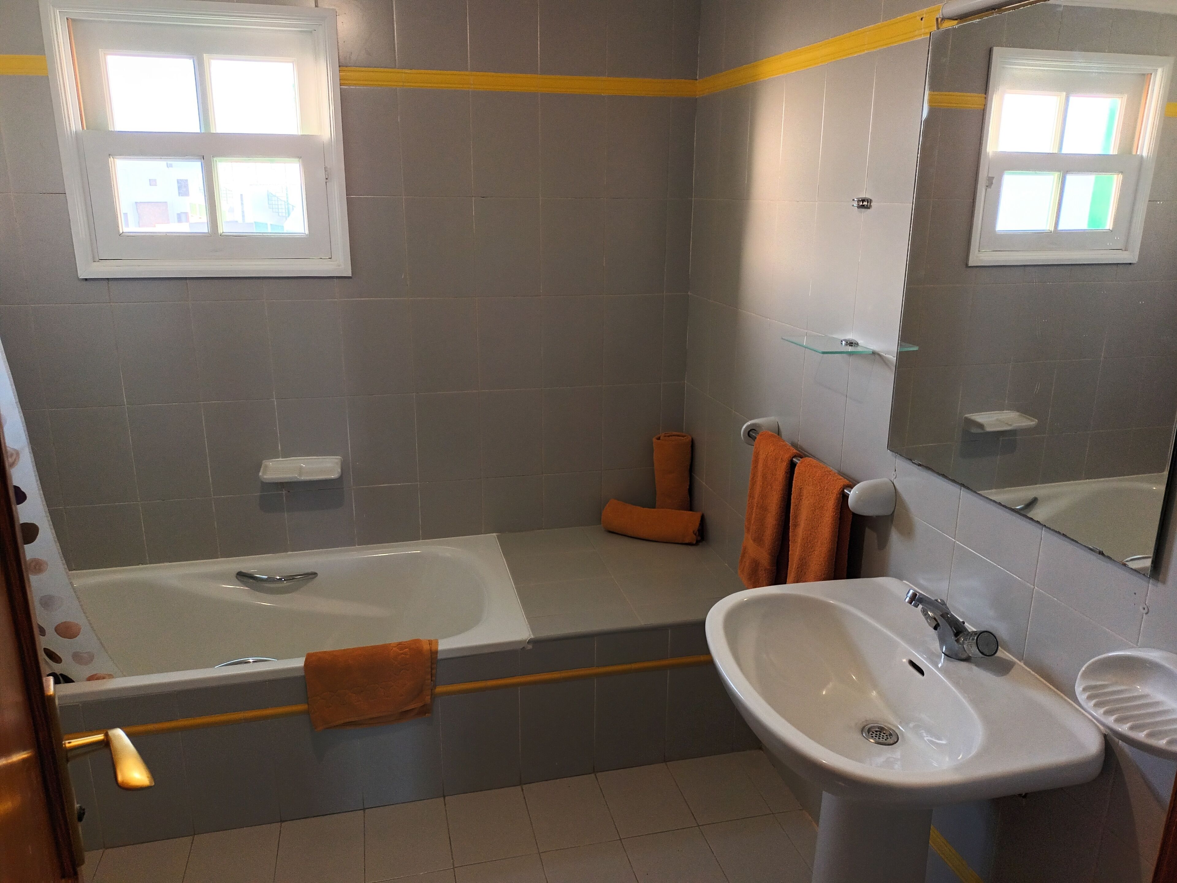 A bathroom with a bathtub, a sink, and a mirror.