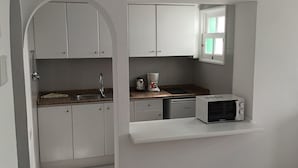 A compact kitchen with white cabinets, a built-in microwave, and a coffee maker.