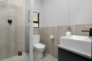 A modern bathroom with a toilet, shower, and bathtub.