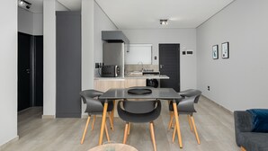 A modern kitchen with a dining area, featuring a large table, chairs, and a coffee machine.