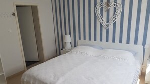 Une chambre à coucher avec un lit, un élément de décoration murale en forme de cœur, une lampe de chevet et un mur à rayures.