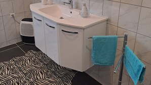 Une salle de bain avec un lavabo blanc, un miroir et deux serviettes posées sur un porte-serviettes.