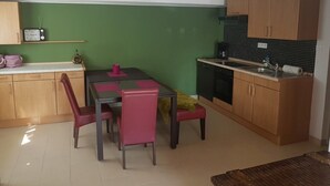 Une cuisine compacte comprenant une table et des chaises, un four à micro-ondes et une machine à café.