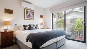 A modern bedroom with a large bed, bedside tables, and a view of the outdoors.