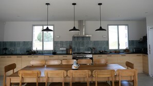 A modern kitchen with a central island, wooden chairs, pendant lights, and a large window. - LA ROTIERE LODGE DU CERVOLET 4-bedroom house in the Loire Valley (Fontaines-en-Sologne)