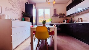 A modern kitchen with white cabinetry, a dining table, and chairs. - Relax in vibrant San Frediano (Firenze)