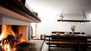 Ein gemütlicher Essbereich mit Kamin, Holzmöbeln und hängenden Lampen.