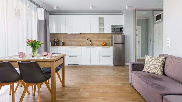 A modern kitchen with white cabinets, a wooden countertop, and a stainless steel refrigerator.