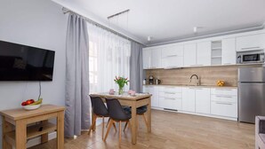 A modern kitchen with white cabinets, a wooden countertop, and stainless steel appliances.