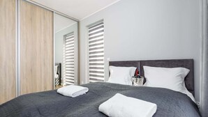 A modern bedroom with a large bed, a wooden wardrobe, and a mirror.