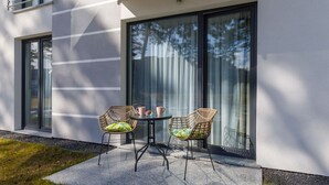 An outdoor seating area with wicker chairs and a table, a glass door, and a modern building facade.