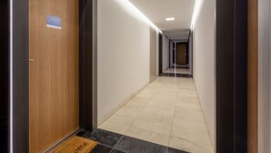 A hotel corridor with a wooden door on the left, a welcome mat, and a tiled floor. - Vacation apartment by the sea, vacation on the island of Usedom, Apartment SUN TOWERS B42 (Świnoujście)