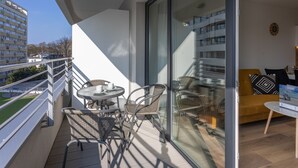 A balcony with a glass door leading to a living area, furnished with a sofa, chairs, and a small table. - Vacation apartment by the sea, vacation on the island of Usedom, Apartment SUN TOWERS B42 (Świnoujście)