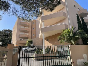 A multi-story building with balconies, a gated entrance, and surrounding greenery. - CAVALAIRE: The Sun of Your Vacation!<br>—a comfortable apartment just 8 minutes from the beach (Cavalaire-sur-Mer)