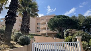 Un immeuble résidentiel à la façade beige, doté de nombreux balcons et d’une entrée sécurisée par un portail.