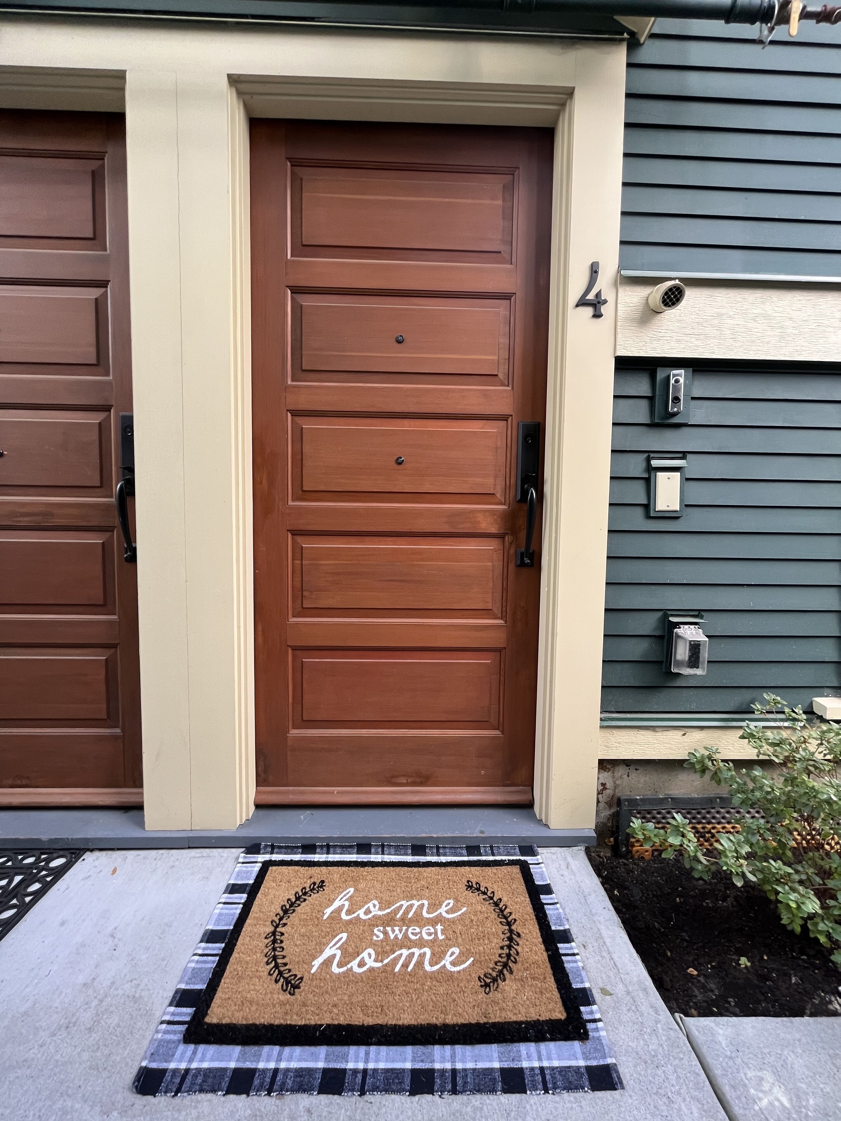 A front door with a doormat that reads "home sweet home" and a mailbox on the right side.