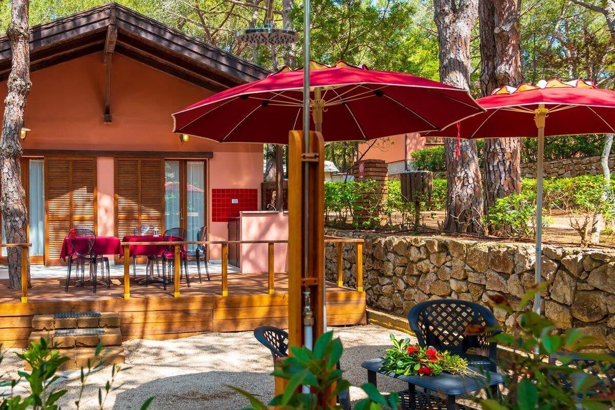 Un patio exterior acogedor con cubierta de madera, sombrillas rojas y una pared de piedra.