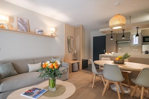A modern living room with a sofa, coffee table, and a dining area with chairs and a table. - Charming renovated apartment near the beach and close to Saint Tropez 5 (Gassin)