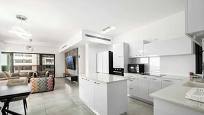 Una cucina moderna con mobili bianchi, un'isola centrale e un'area pranzo con tavolo e sedie.