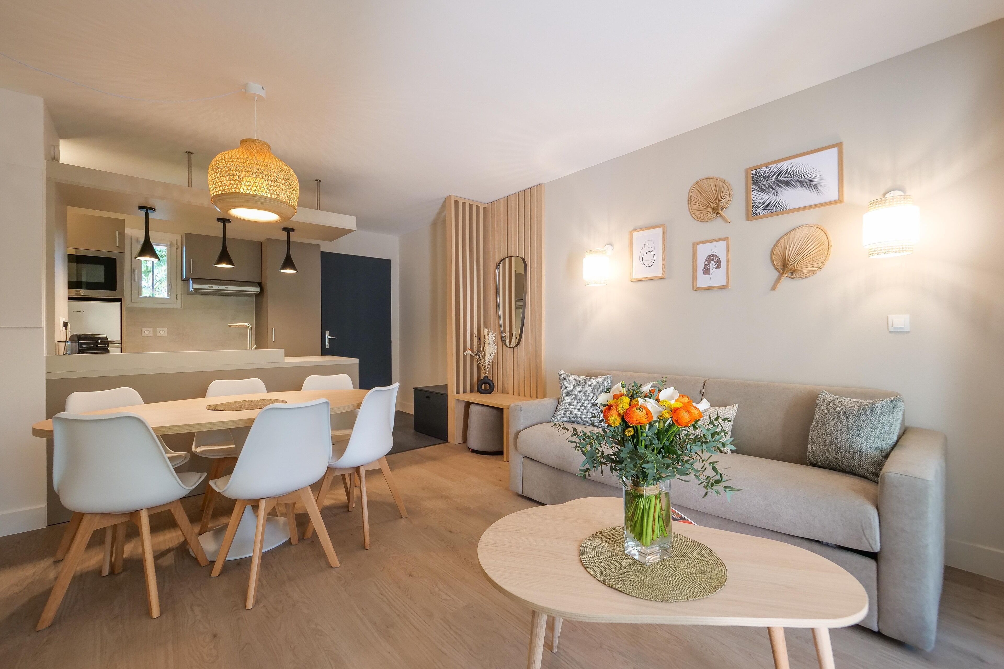 A modern living room with a dining area, a sofa, and a coffee table with a vase of flowers.