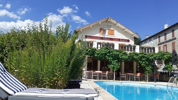 Un hotel con piscina, sillones de descanso y letrero de restaurante.