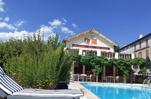 Un hotel con piscina, sillones de descanso y letrero de restaurante.