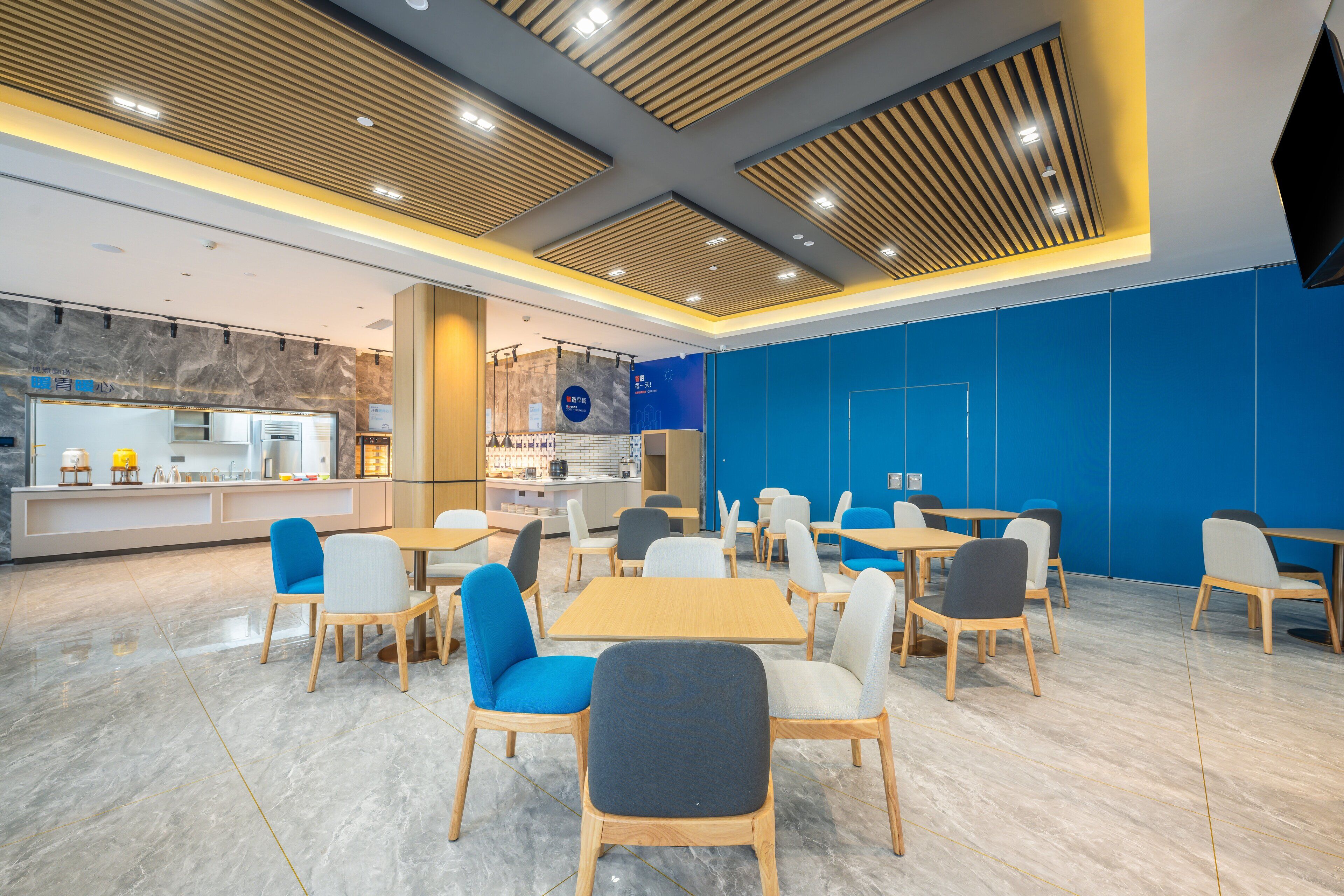 A modern cafe with wooden tables and chairs, a marble floor, and a blue accent wall.