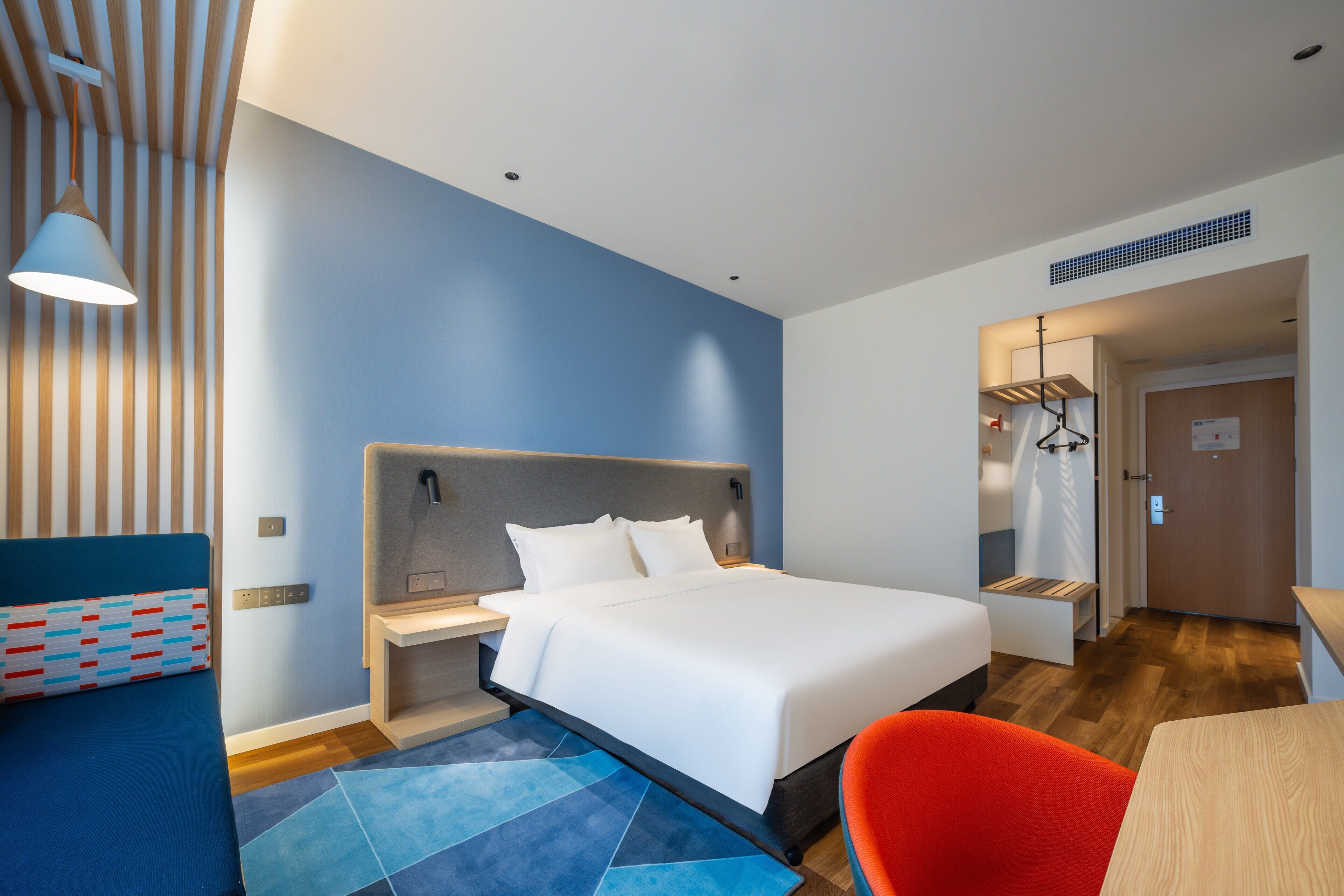 A modern hotel room with a large bed, a desk, and a chair.