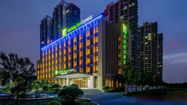 Un bâtiment de la chaîne Holiday Inn Express, doté d’un design moderne, avec une entrée imposante et une enseigne lumineuse.