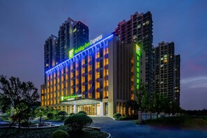 A multi-story hotel with a prominent 'Holiday Inn Express' sign, a covered entrance, and surrounding greenery. - Holiday Inn Express Jurong Xianlin by IHG (Zhenjiang)