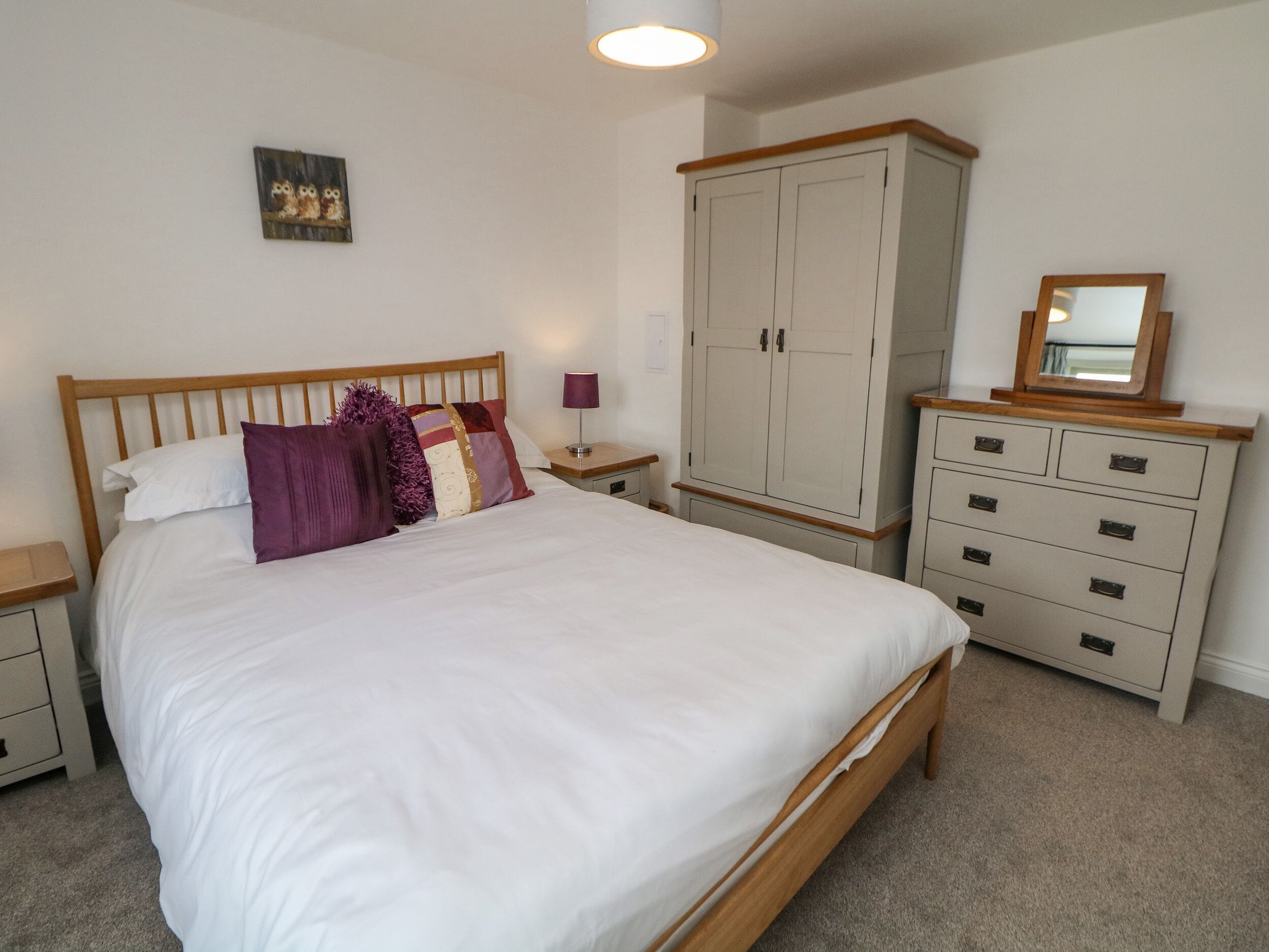 Une chambre à coucher avec un grand lit, une armoire, une table de chevet et un miroir.