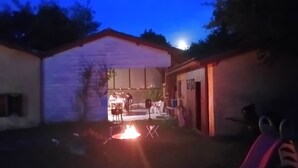 Ein Garten mit Feuerstelle, Esstisch und Stühlen.