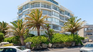 A multi-story hotel with balconies, surrounded by palm trees and rocks. - Seacliffe 307 (Cape Town)