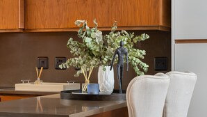 A kitchen with wooden cabinets, a marble countertop, and two bar stools. - Seacliffe 307 (Cape Town)