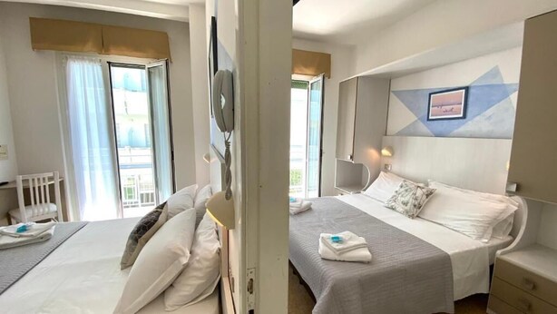 A hotel room with two beds, a desk, and a chair.