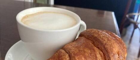 A croissant and a cup of coffee on a table.