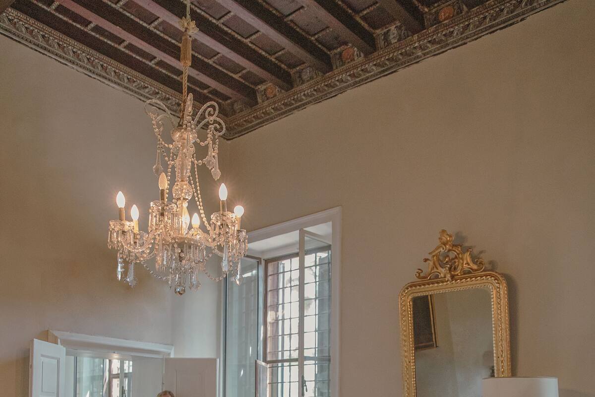 A spacious room with a chandelier, a fireplace, and a large mirror.