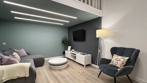 A modern living room with a grey sofa, a round coffee table, a white TV stand, and a floor lamp. - Underfloor heating  & Free Parking in the city center (Debrecen)