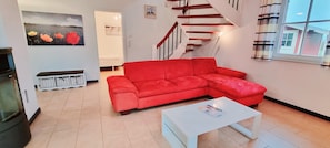 A living room with a red sofa, a white coffee table, and a staircase.