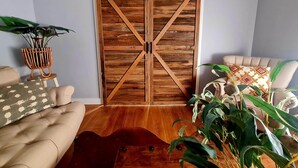 Una stanza con una porta a scorrimento in legno, un divano, un tavolino da caffè e una pianta in vaso.