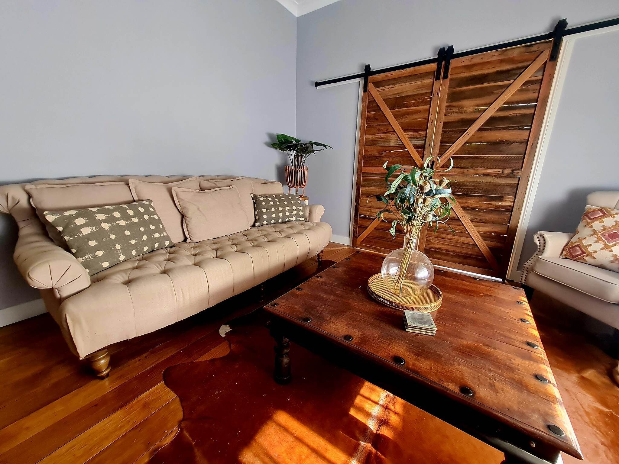 Ein Wohnzimmer mit einer Couch, einem Couchtisch und einer Schiebetür im Bauernhausstil.