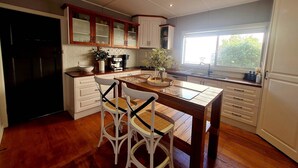 Una cucina con mobili in legno, un tavolo da pranzo con sedie, una finestra con vista su del verde e un lavello.