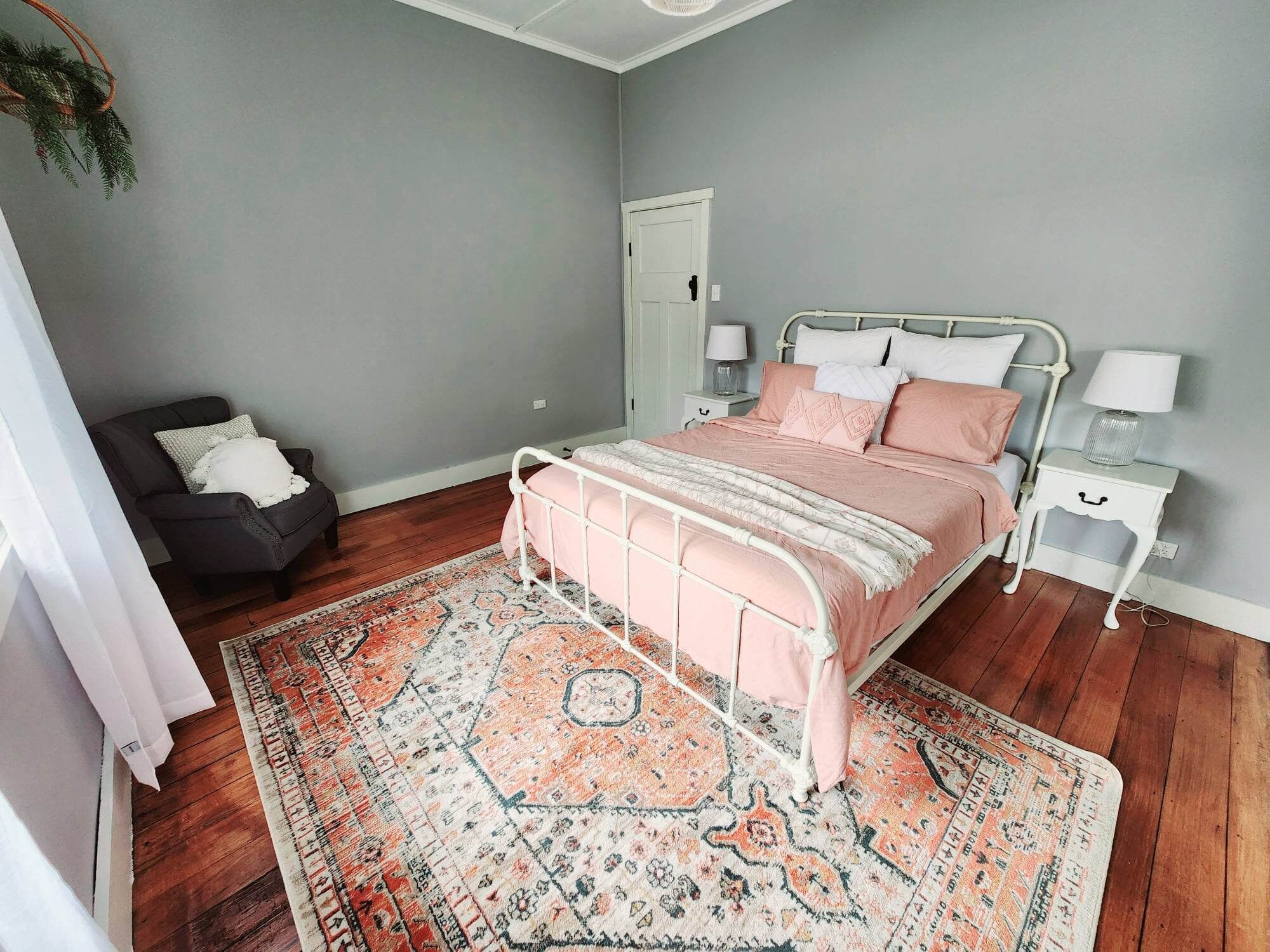 A bedroom with a bed, nightstands, a chair, and a door.